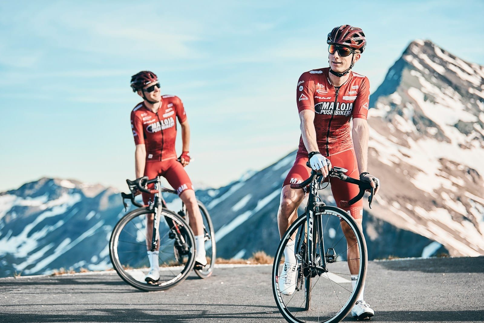 Photo by Hannes Glöckl two men biking on road viewing mountain